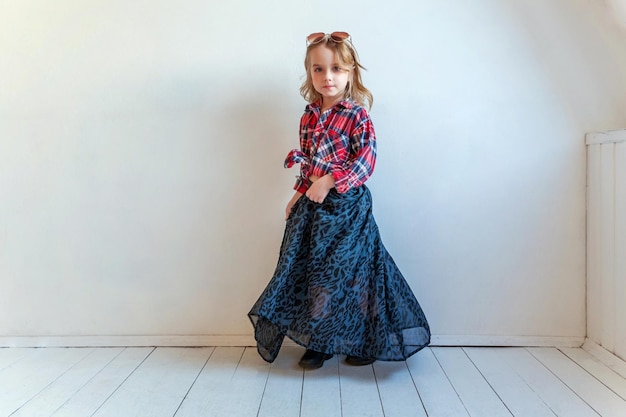 Little girl standing against white wall background in bright room