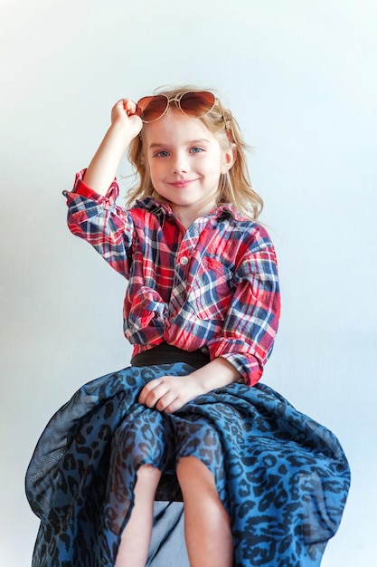 Little girl standing against white wall background in bright room