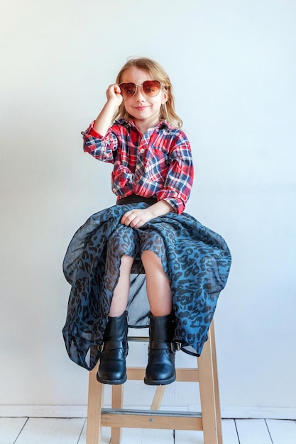 Little girl standing against white wall background in bright room