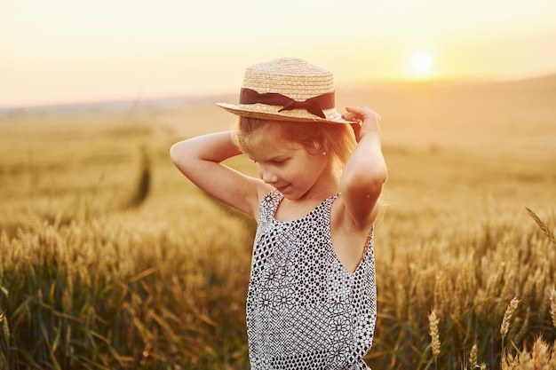 Little girl standing on the agricultural field at evening time Conception of summer free time