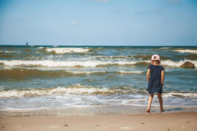 Little girl standing alone watching the waves on the beach of a Baltic sea