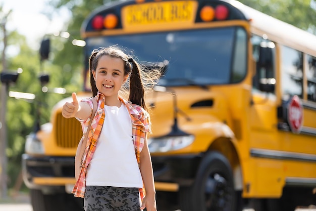 Little girl standing by a big school bus door with her backpack.