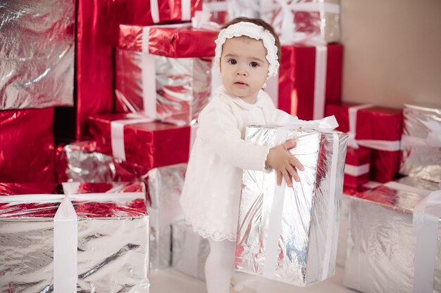 Little girl standing by christmas gift boxes