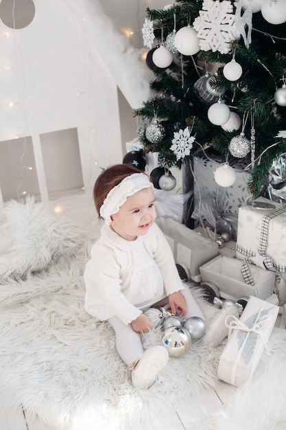 Bambina in piedi vicino all'albero di natale decorato