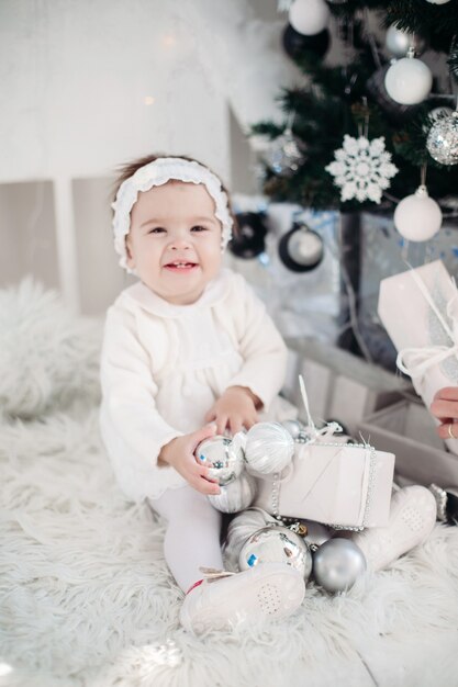 Bambina in piedi vicino all'albero di natale decorato