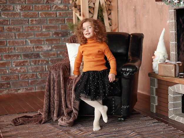 Little girl standing by the fireplace and pointing at you