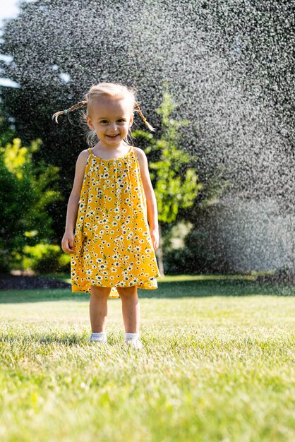 Foto una bambina in piedi davanti a uno spruzzatore d'acqua