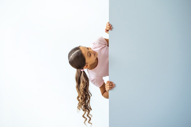 The little girl standing over the wall on white background