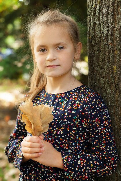 little girl stands in a city Park and holds a cast oak tree. autumn walks.