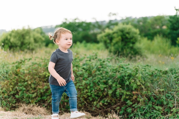 A little girl stands on a rock in a field