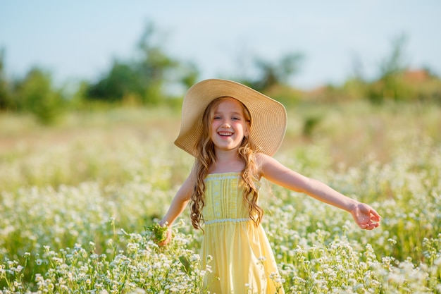 Little girl in a straw hat in the field