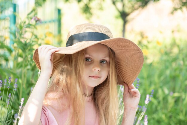 Little girl in a straw hat surrounded by lavender flowers