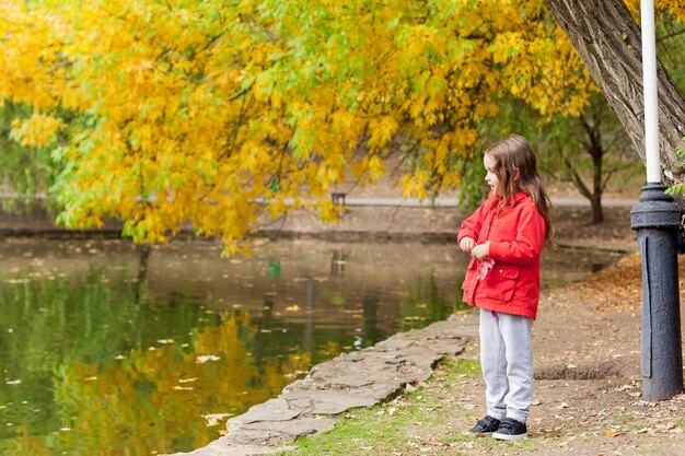 寒い晴れた秋の日に公共の公園で散歩中に小さな女の子