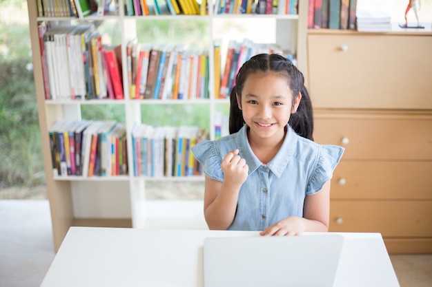 写真 ライブラリーと戦闘の机の上でノートパソコンを持つ少女の学生