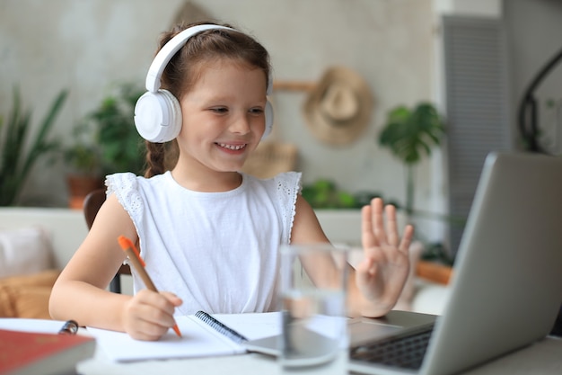 Little girl studing online with video call teacher. Distance learning in epidemic of Covid-19 coronavirus.