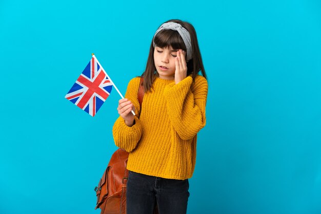 Little girl studying English isolated on blue wall with headache