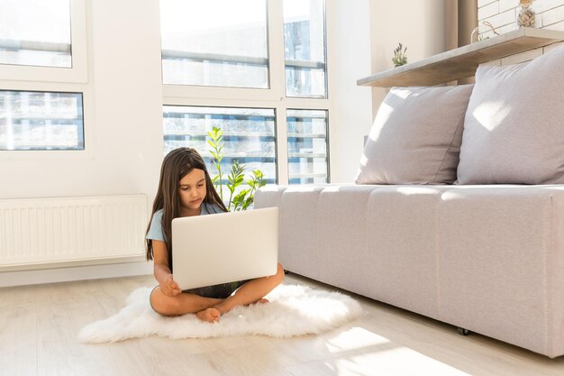 Little girl studying online using her laptop at home