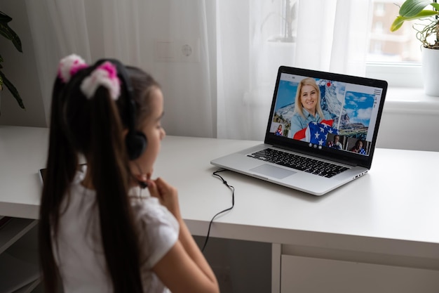 Little girl studying online using her laptop at home.