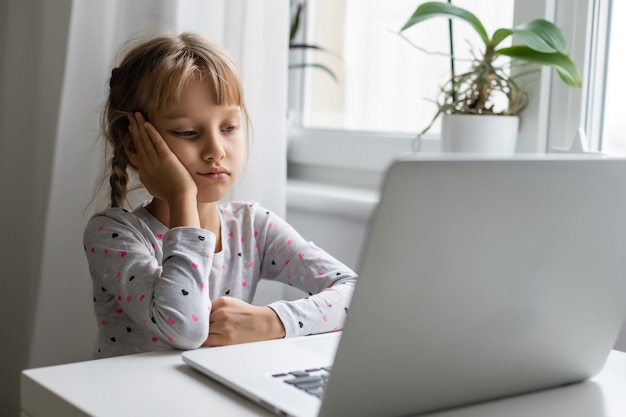 Little girl studying online using her laptop at home