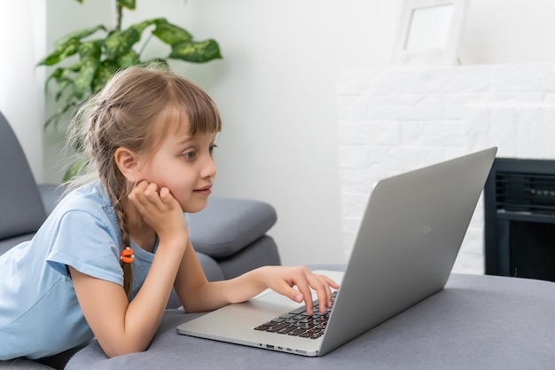 Bambina che studia con il computer, bambina con il computer portatile online.