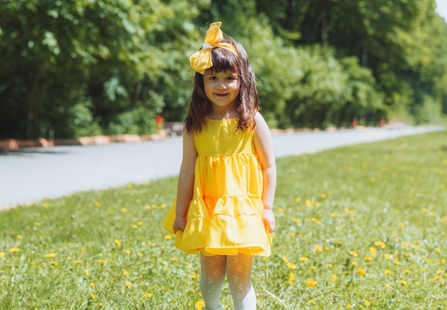 夏の黄色いドレスを着た少女が、タンポポの花輪の公園の芝生でシャボン玉をキャッチします