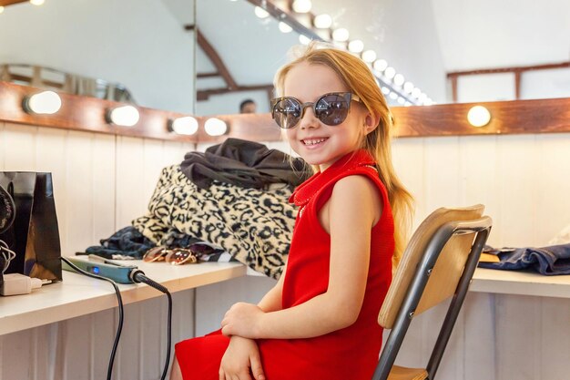 Little girl in sunglasses near mirror