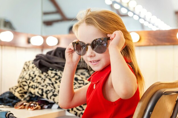 Little girl in sunglasses near mirror