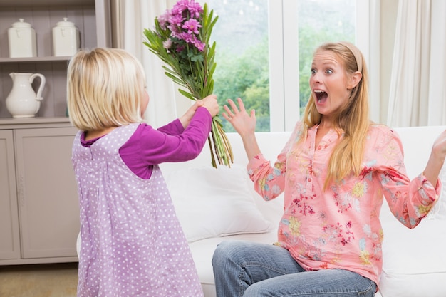 Little girl surprising her mother with flowers 