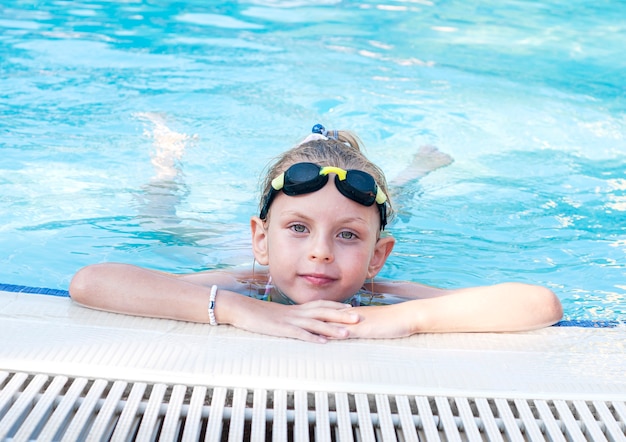 Bambina in occhiali da nuoto nuota in piscina