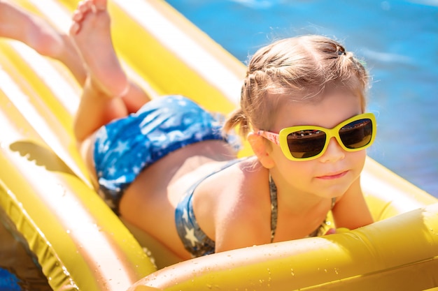 Little girl swimming on inflatable beach mattress.