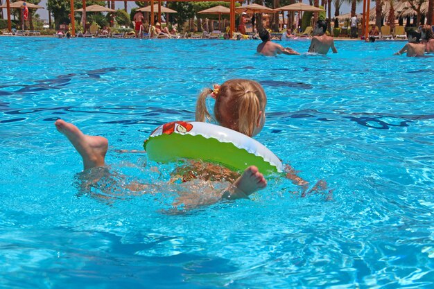 Little girl swimming in water lying on inflatable circle on summer holidays at sea rest on tropical resort happy childhood in resort teenager girl relaxing on rubber circle during holidays