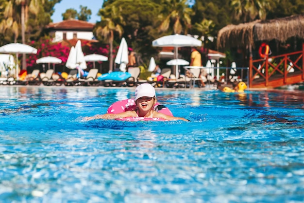 Bambina che nuota con anello galleggiante in piscina