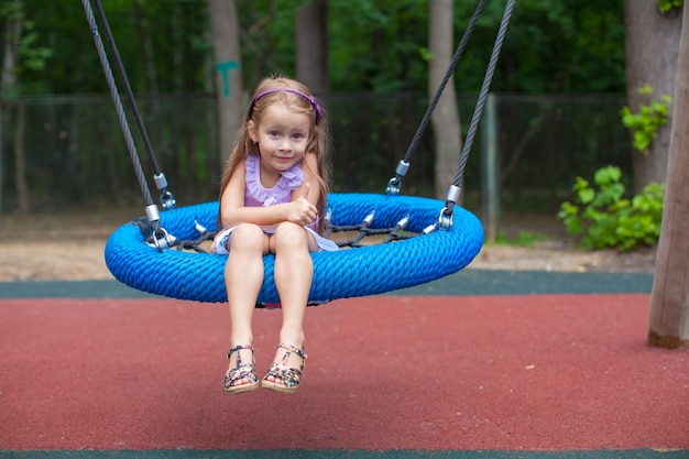 Маленькая девочка на качелях в парке развлечений