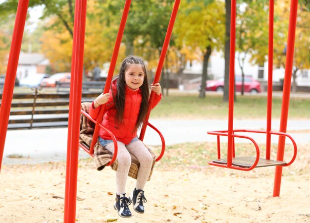 Little girl on swing in city park