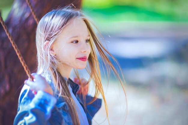 Little girl swinging on a swing outdoors in the forest