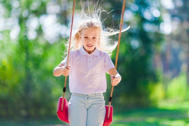 Little girl swinging on a swing outdoors in the forest