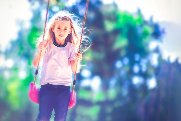 Little girl swinging on a swing outdoors in the forest