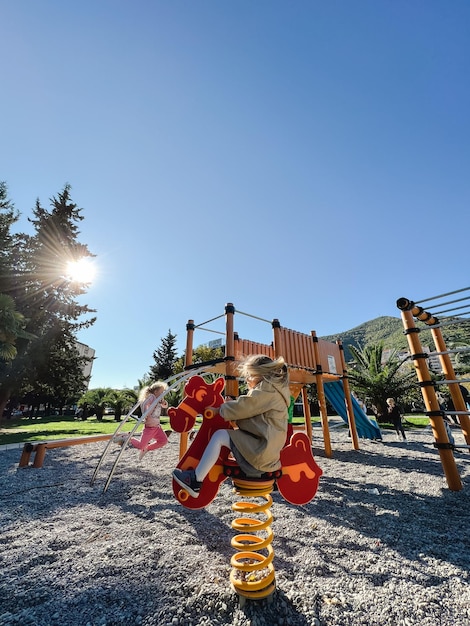 Little girl swings on a springswing with her hair blowing in the wind