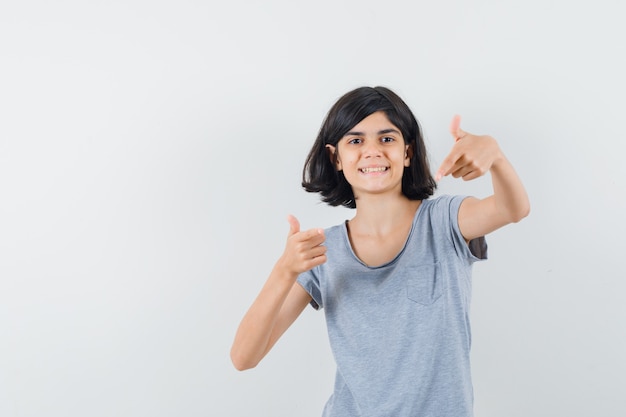 Little girl in t-shirt pointing at camera and looking glad , front view.