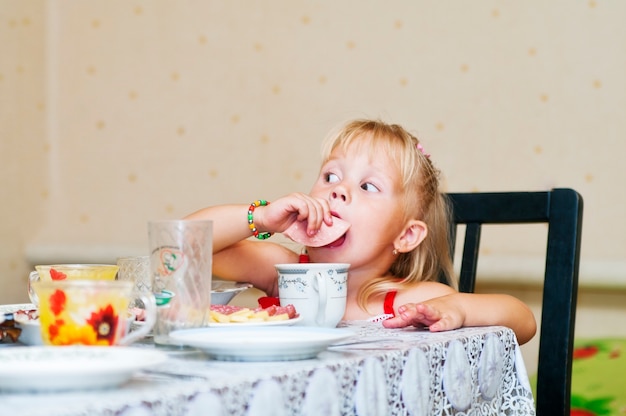 Foto bambina a tavola che mangia salsiccia