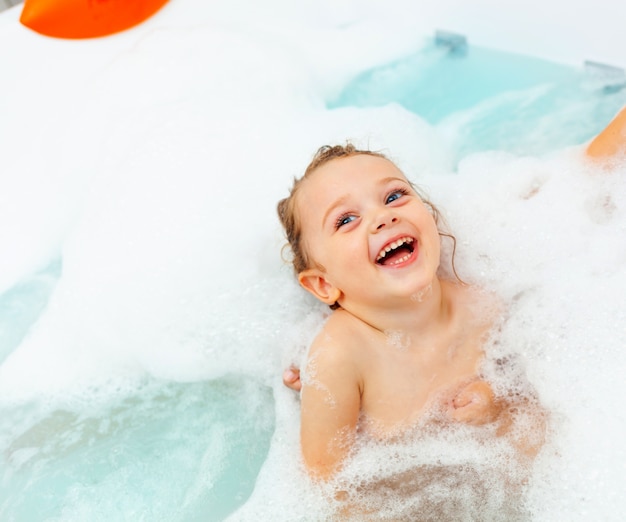 Little girl takes a bath in a hydromassage bathtub.