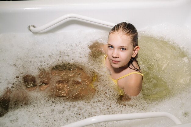어린 소녀는 미네랄 목욕에서 절차를 걸립니다. 환자는 미네랄 펄 목욕으로 물 치료를 받습니다.