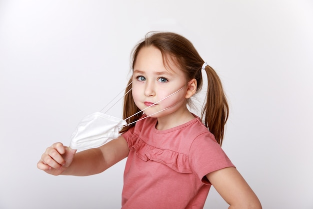 Little girl taking away a medical mask to breathe better