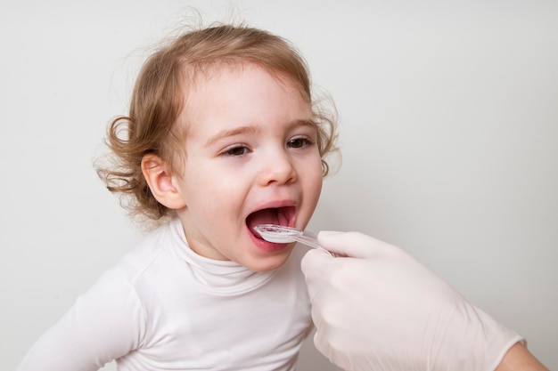 Bambina che cattura la medicina con il cucchiaio