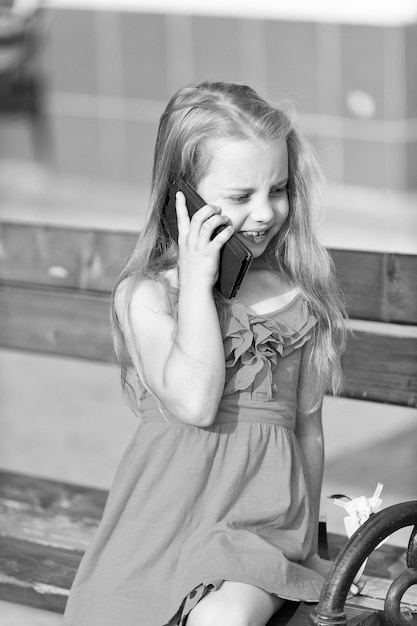 Little girl talk on cell phone on park bench summer Child and new technology childhood concept communication