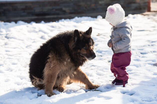 Little girl talking with her dog on winter walk