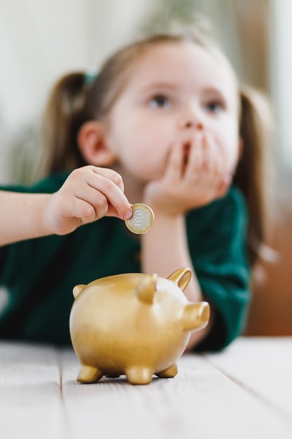 お金を使って貯金箱にコインを入れることを考えている少女