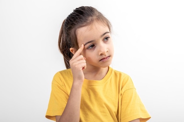 Little girl thinking holding finger at temple isolated on white background