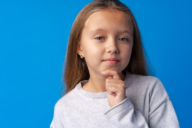 Little girl thinking and looking up over blue background