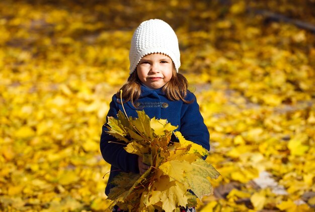 Little girl throwing autumn leaves